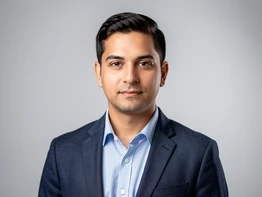 A polished portrait of a person in business casual attire against a smooth light-gray studio backdrop, shoulders squared to the camera, expression calm and confident. Soft frontal studio lighting from two diffused sources eliminates harsh shadows and renders skin tones evenly. Style: corporate headshot photography. Mood: professional and trustworthy.