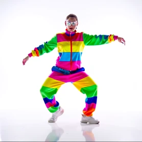 A person mid-dance in a bright white studio, caught in a sharp freeze-frame pose with one arm extended and knees bent, wearing a colorful tracksuit. Ring-light illumination creates a clean, even glow across their face with a subtle catchlight in each eye. The floor is polished white and reflects the figure softly. Style: social media content photography. Mood: energetic and fun.